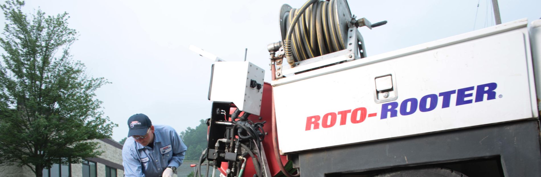 A Roto-Rooter professional plumber holding a hose line into a storm drain