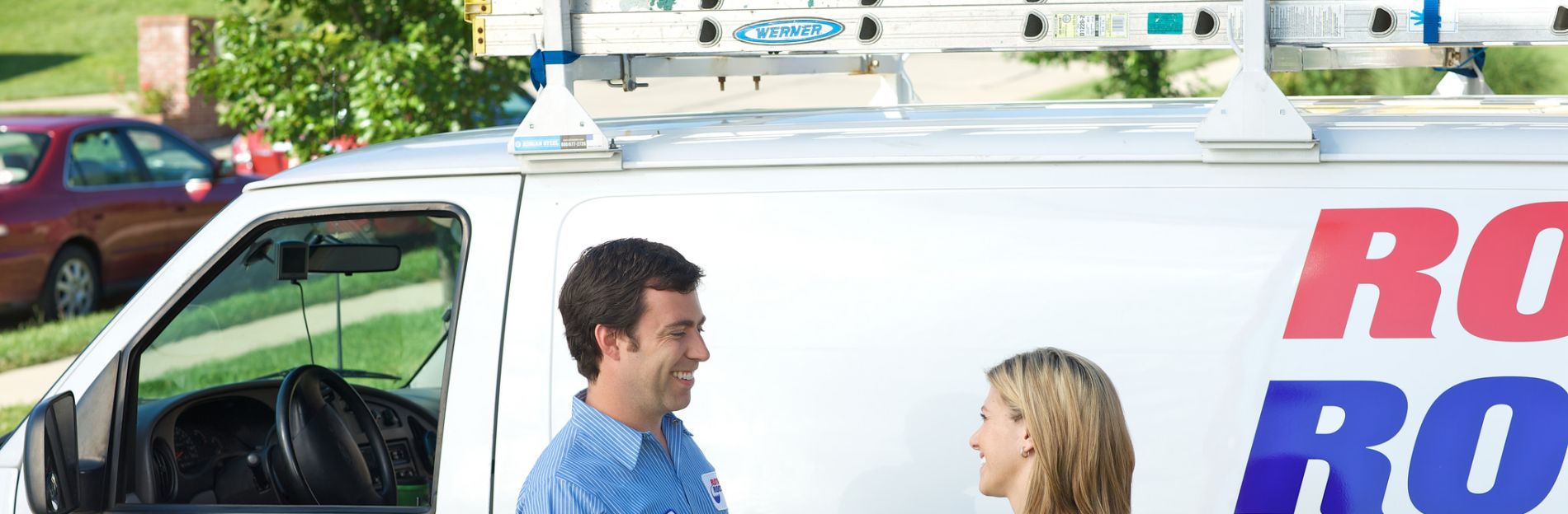 A Roto Rooter plumber standing in front of a work van shaking hands with a client after providing excellent service