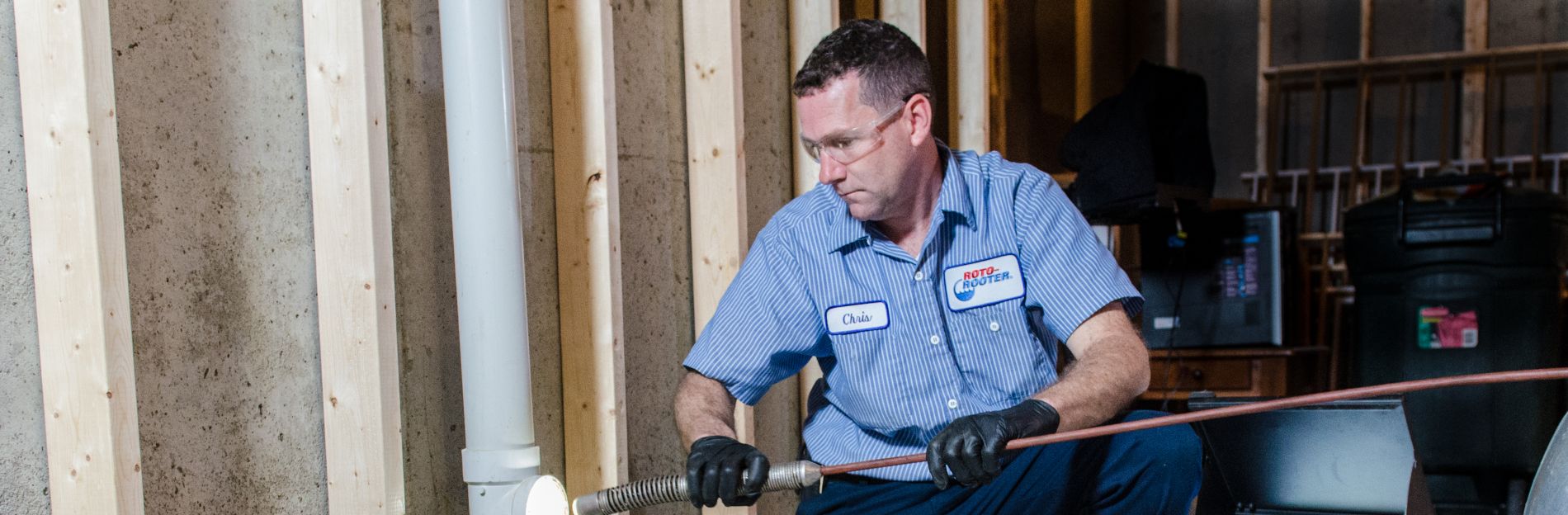 Roto Rooter plumber working with tools and a Roto Rooter tool in a new build home
