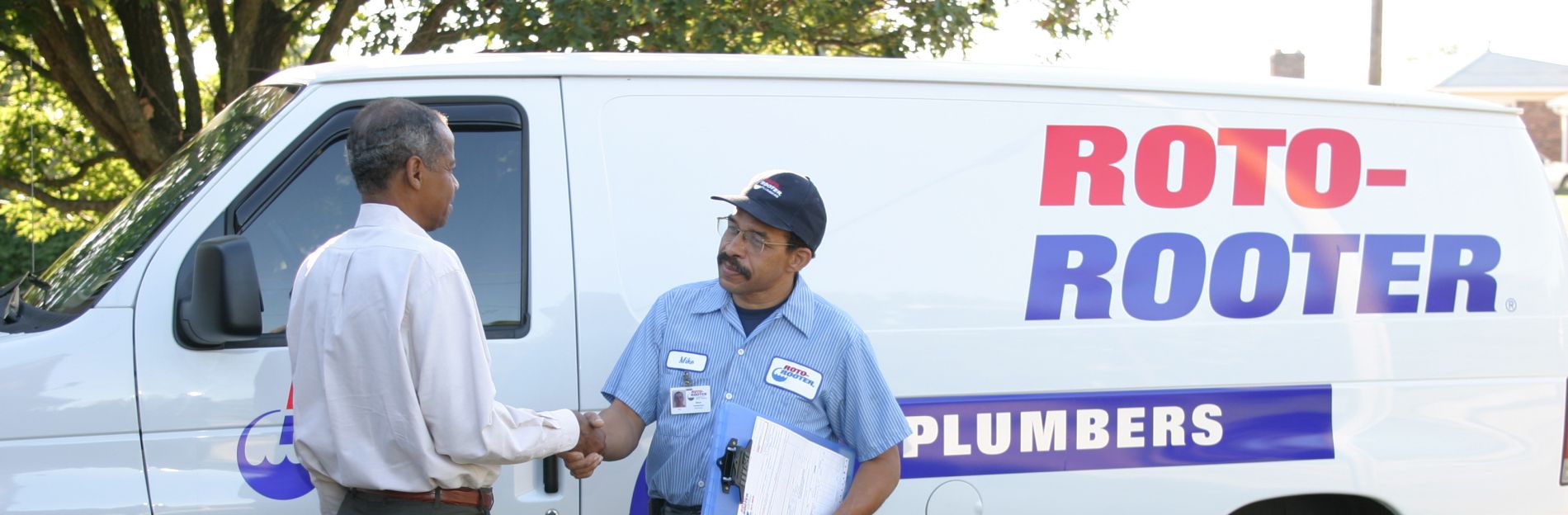 Roto-Rooter Plumber shaking hands with a happy customer in the front yard