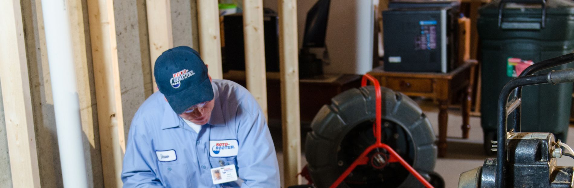 Experienced plumber using a Roto Rooter tool to clean a plastic pipe