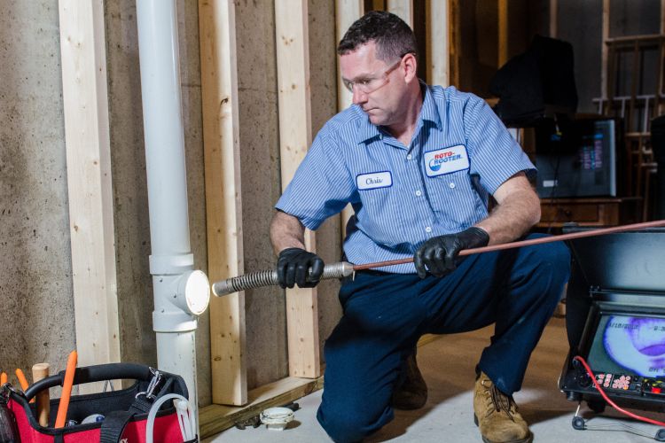 Plumber with Roto Rooter using a Roto Rooter to clean a home's piping